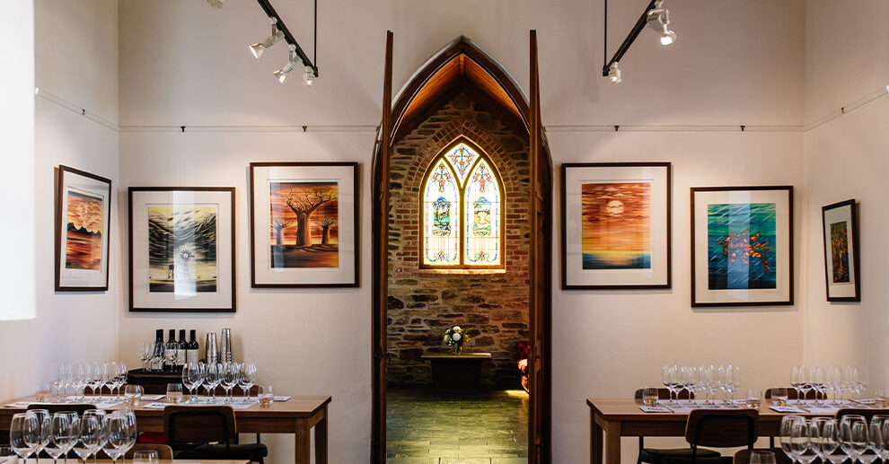 Looking through Chapel Hill's Cellar Door, across tables set for wine tasting, to the distinct arched stained glass window